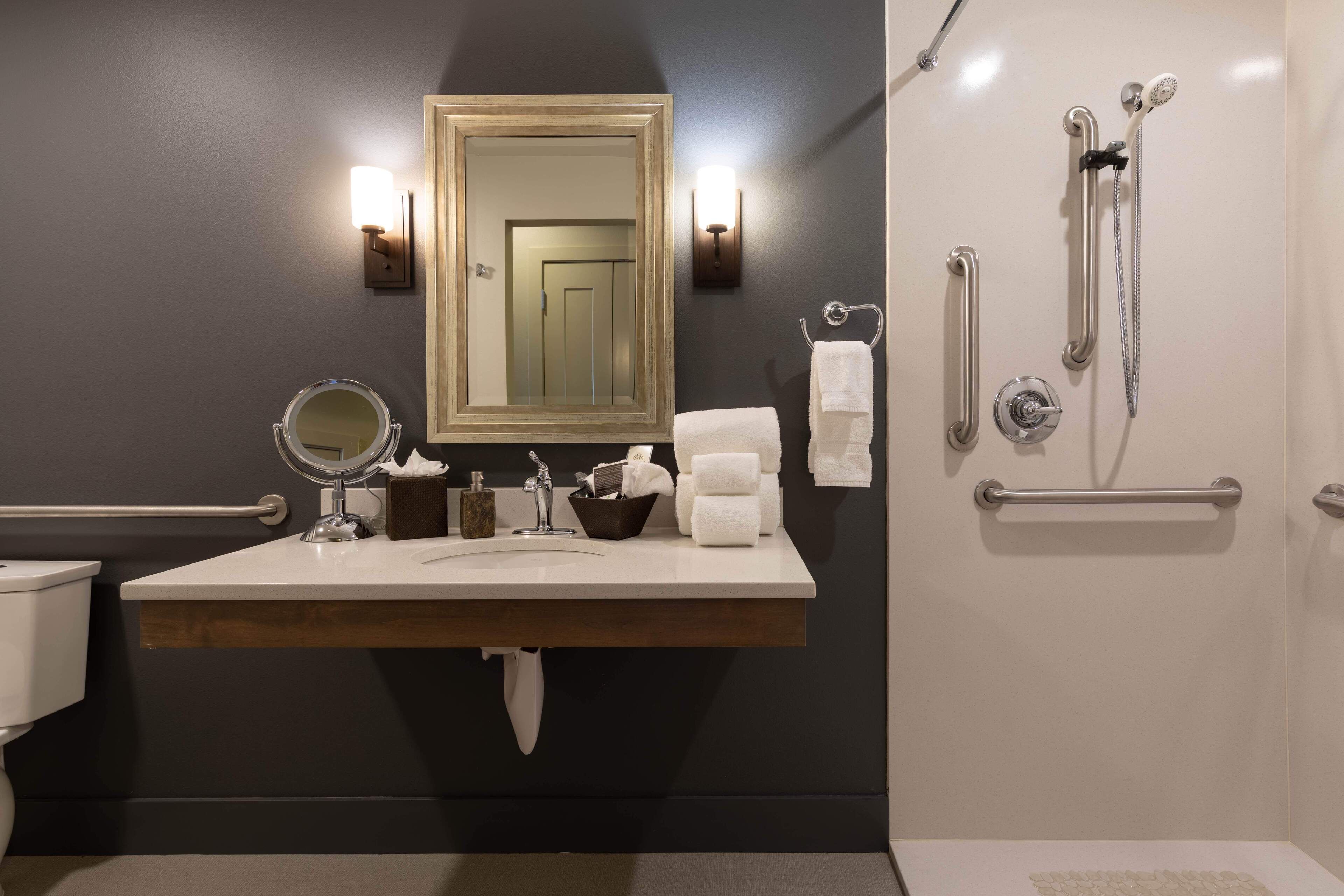 Ein modernes Badezimmer mit großem Spiegel, Waschbecken, Toilette und Duschbereich.