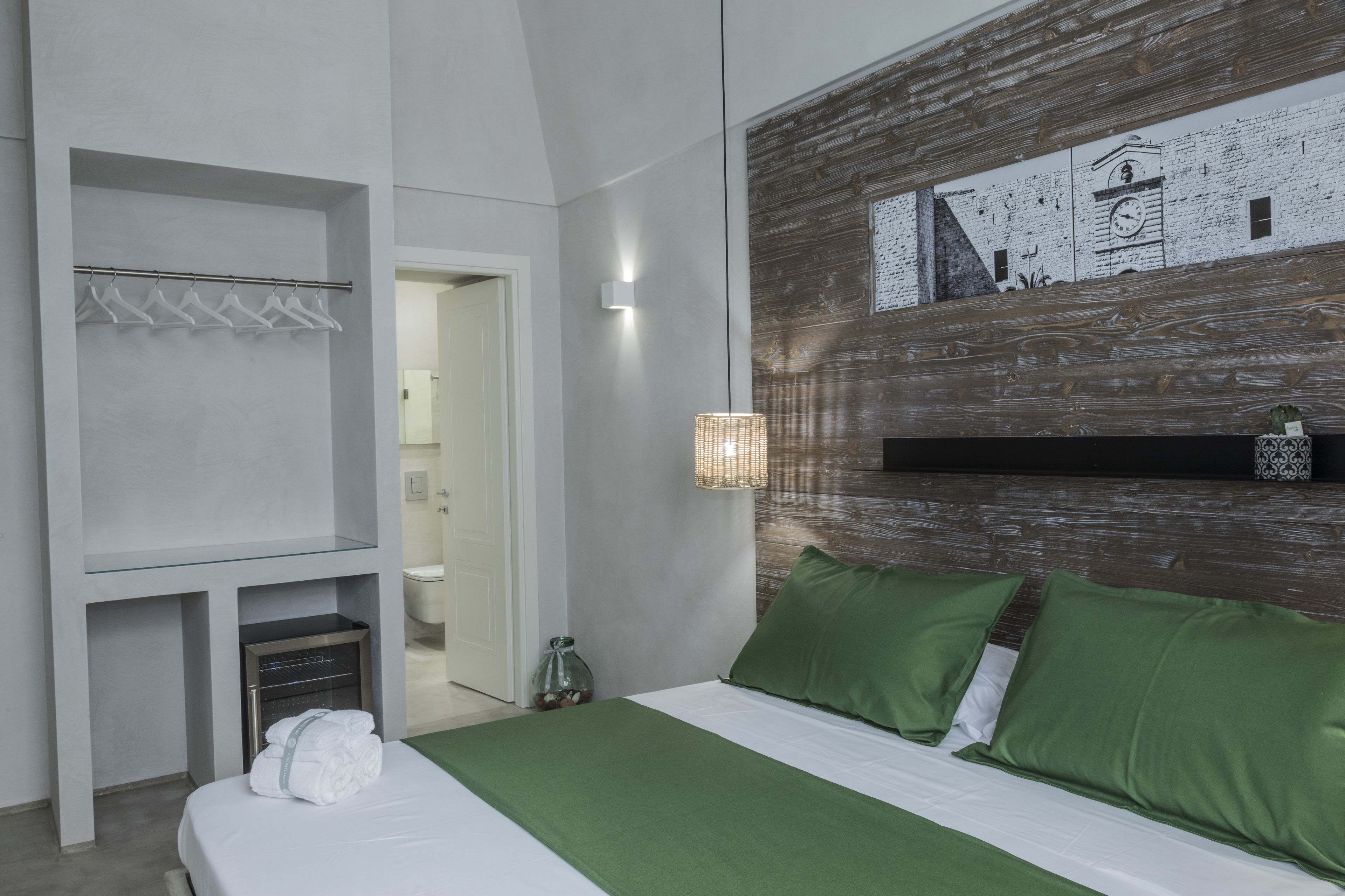 A modern hotel room with a bed, a built-in wardrobe, and a wall-mounted clock.