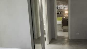 A bedroom with a bed, a mirror, and a hallway leading to a bathroom.