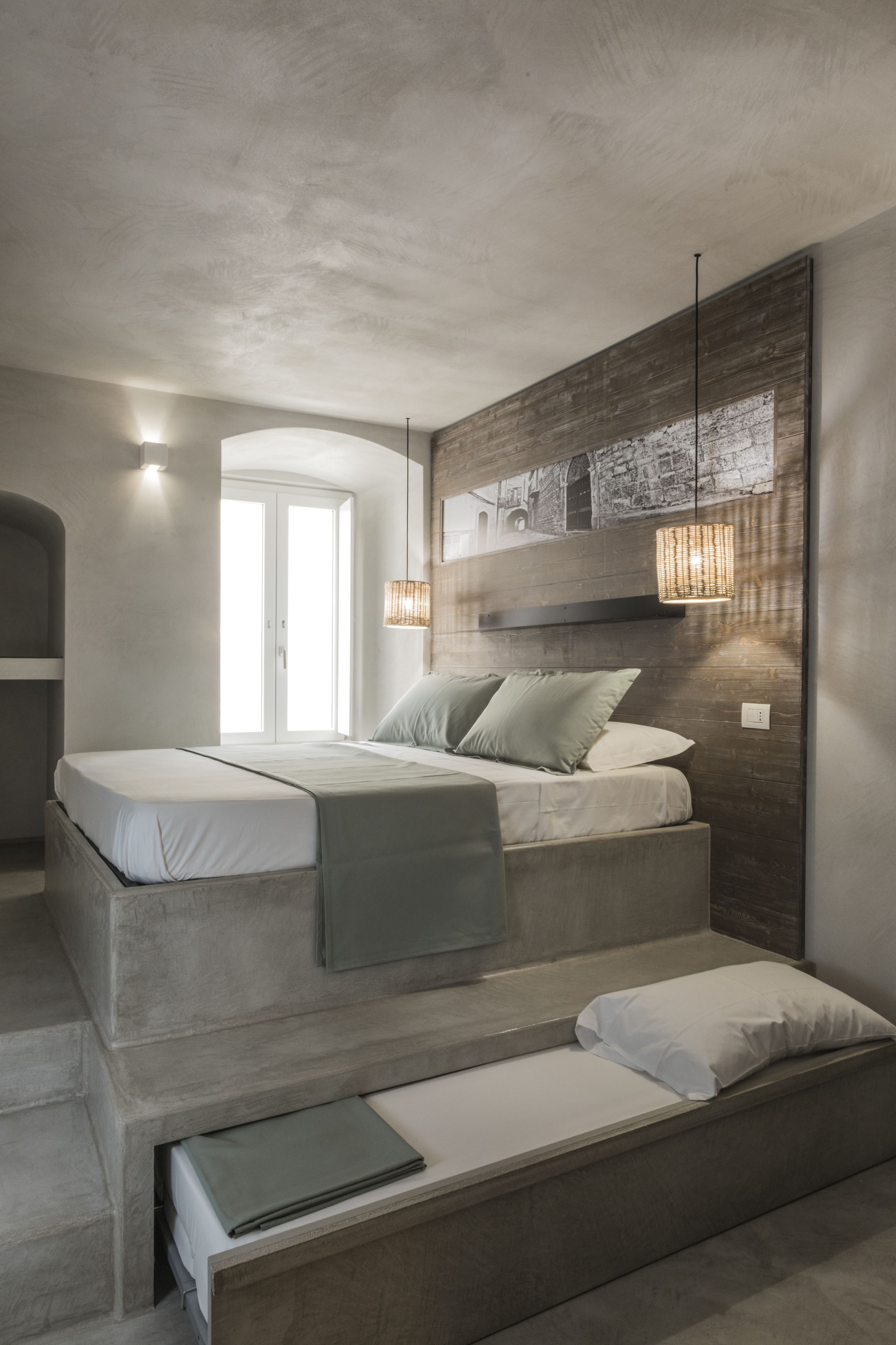 A modern bedroom with a bed, bedside tables, and a large wall-mounted artwork.