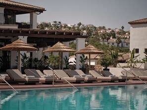 Una piscina al aire libre de temporada, sombrillas, tumbonas