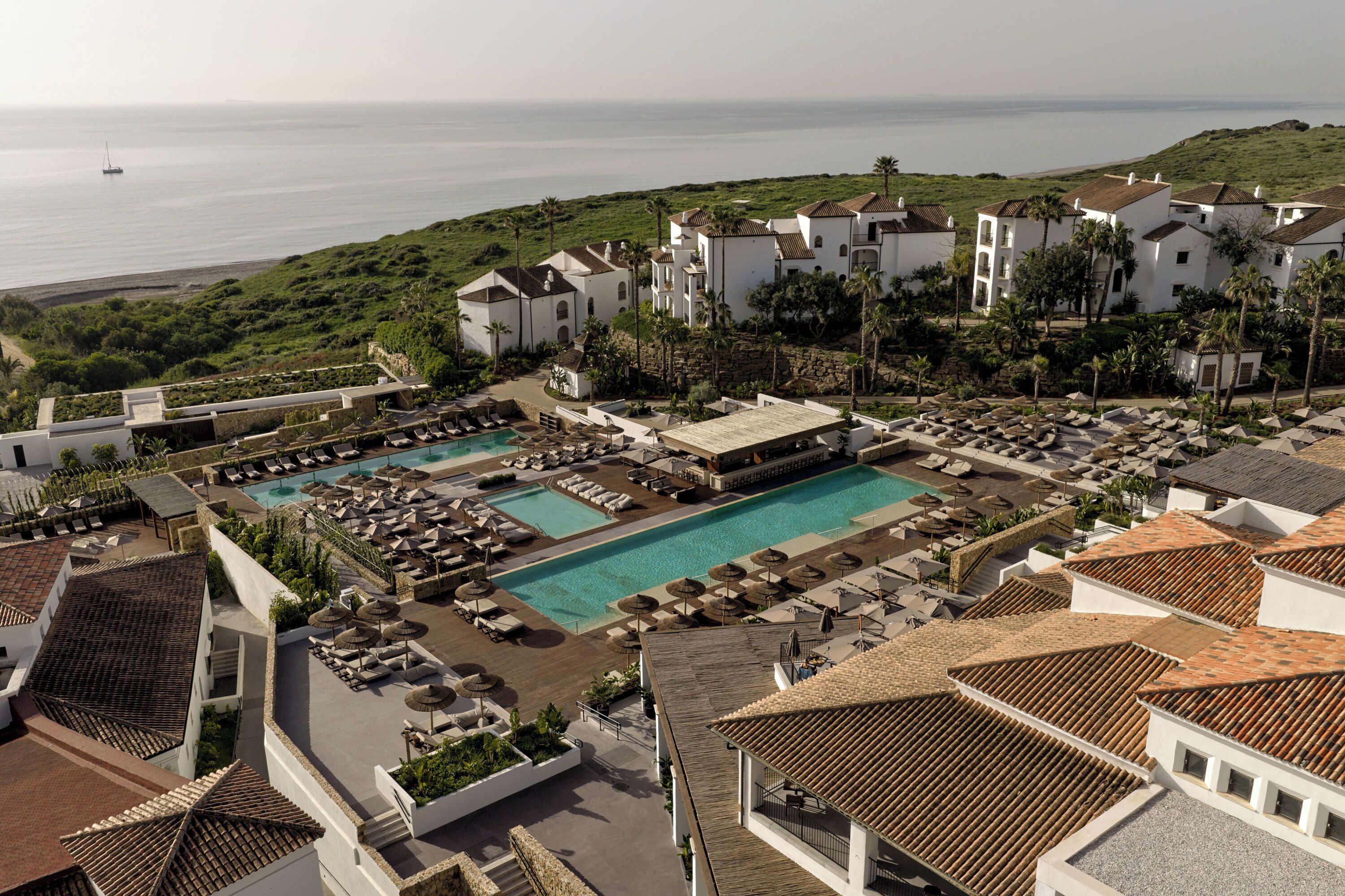 Ein Resort mit mehreren Pools, Liegebereichen und Blick aufs Meer.