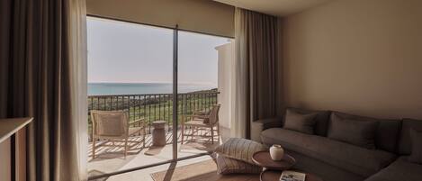 A spacious balcony with a view of the sea, furnished with a sofa, chairs, and a small table.