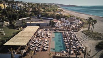 Un resort con piscina, tumbonas y vistas a la playa.