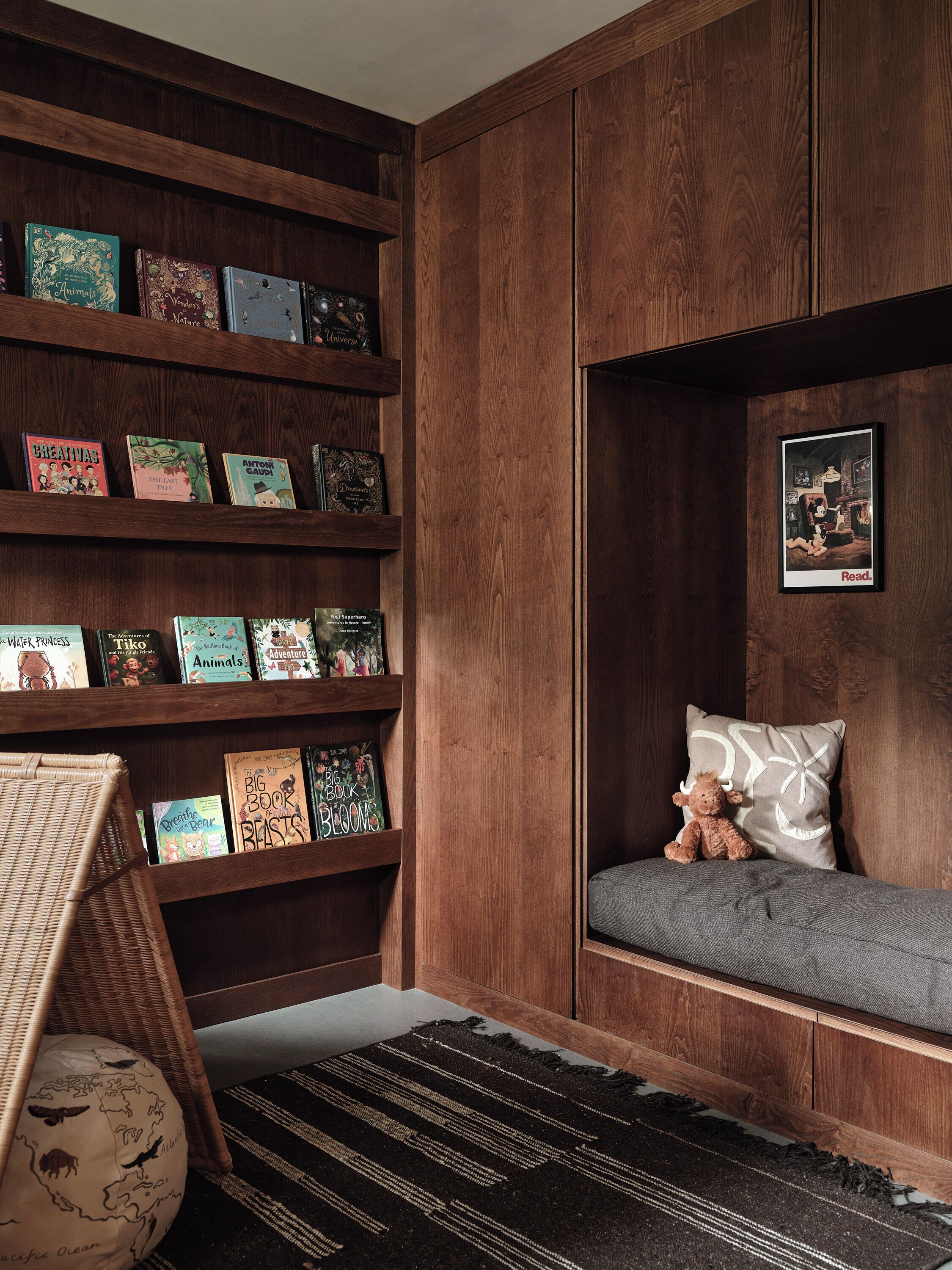 A cozy reading nook with a bookshelf, a plush sofa, and a framed picture on the wall.