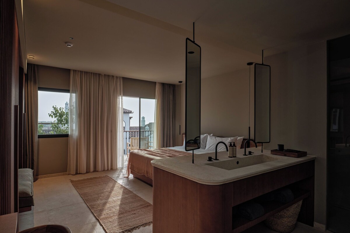 Une salle de bain moderne avec un grand lavabo, deux miroirs et une vue sur la ville par la fenêtre.