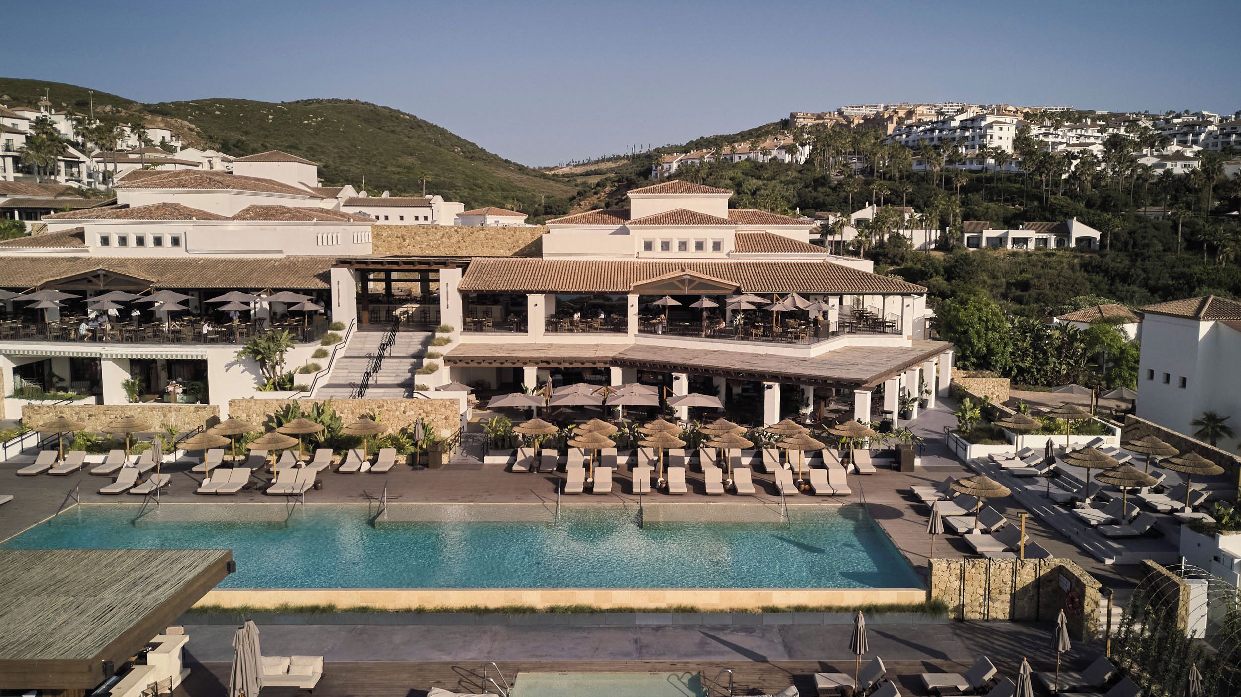 Un resort con piscina, sillas de descanso y zonas de comedor al aire libre.