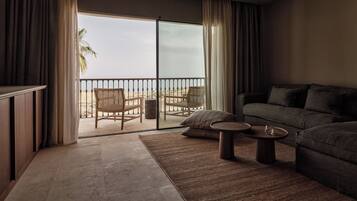 Una sala moderna con un gran ventanal corredizo que da a un balcón con vistas a la playa.