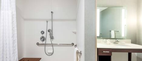 A bathroom with a shower, a sink, a mirror, and a towel rack.