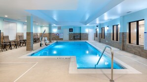 An indoor swimming pool with clear lane markings, a lifeguard chair, and a sign indicating the pool's depth.