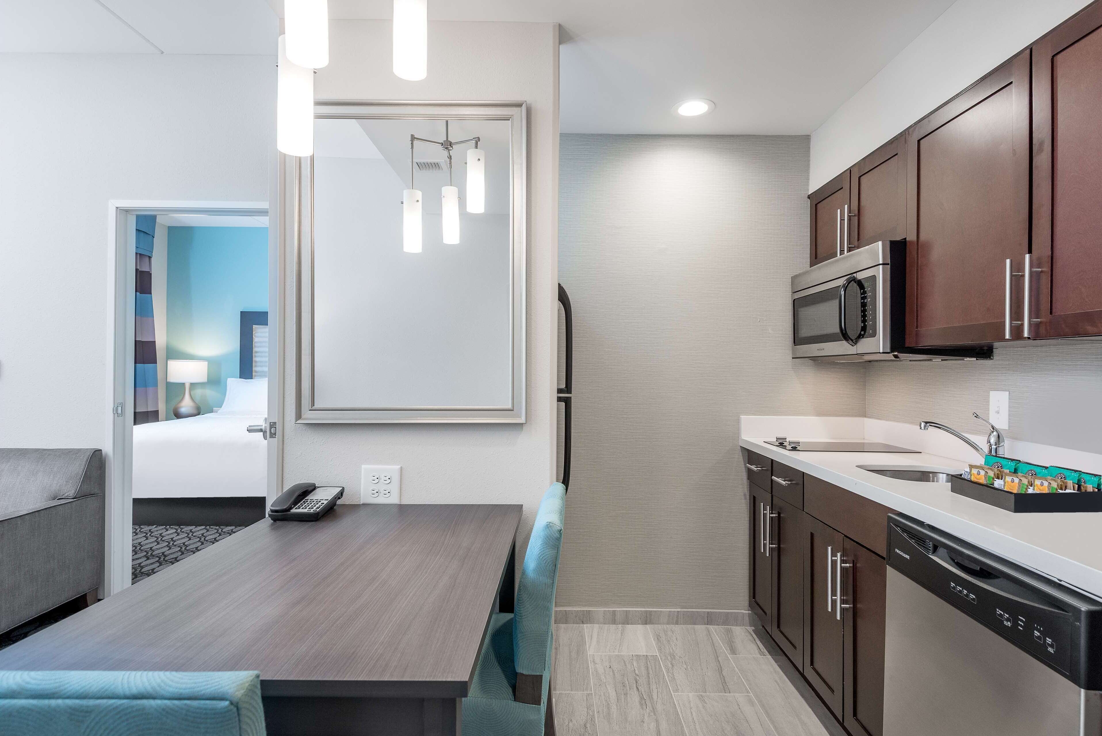 Ein modernes Hotelzimmer mit Essbereich, einer Küche inklusive Mikrowelle und Geschirrspüler, und einer Tür zum Badezimmer.