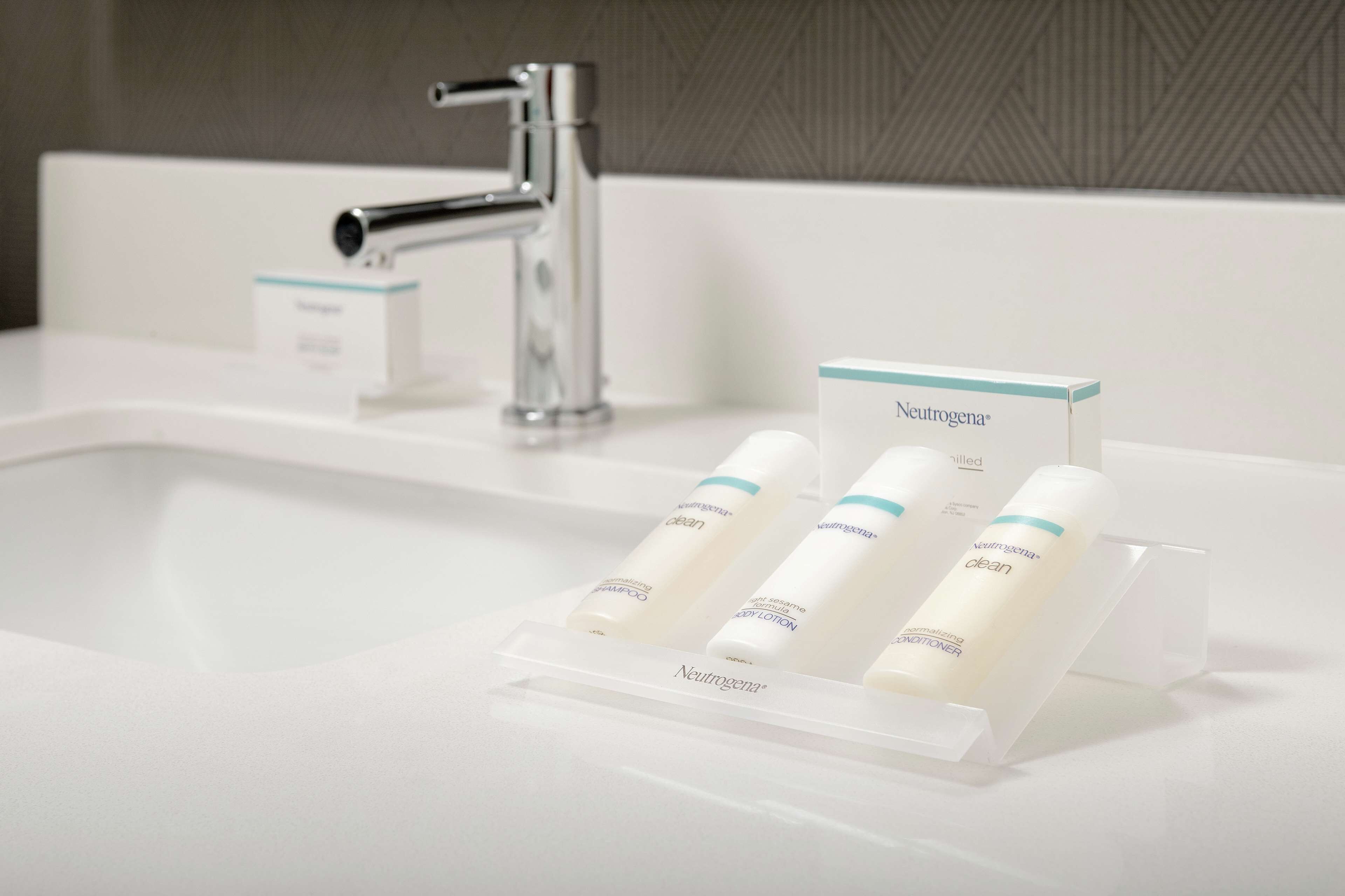 Un lavabo de salle de bain avec un robinet chromé et un présentoir de produits de soins de la peau de la marque Neutrogena.