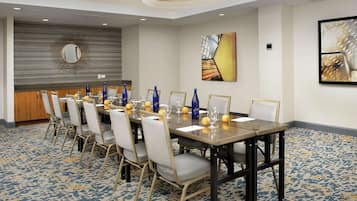 Uma sala de conferência com uma mesa comprida, cadeiras e um espaço bar.