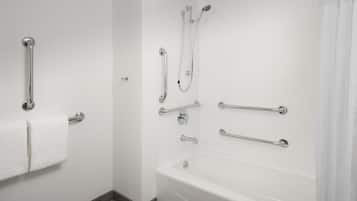 A bathroom with a white bathtub, grab bars, and a towel rack.