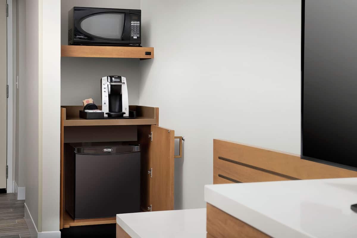 Una kitchenette compacta con microondas, cafetera y refrigerador.