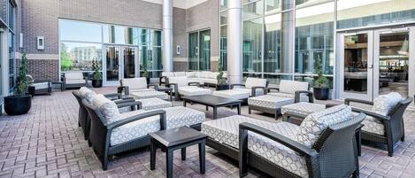 A spacious outdoor seating area with wicker furniture and potted plants.