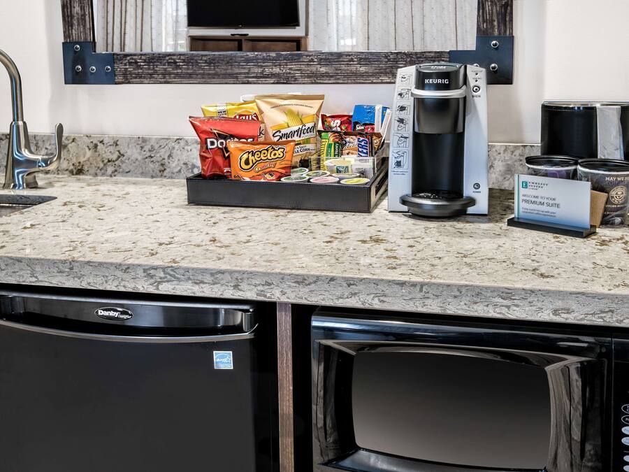A kitchen counter with a coffee maker, a dish soap dispenser, and a bag of snacks.