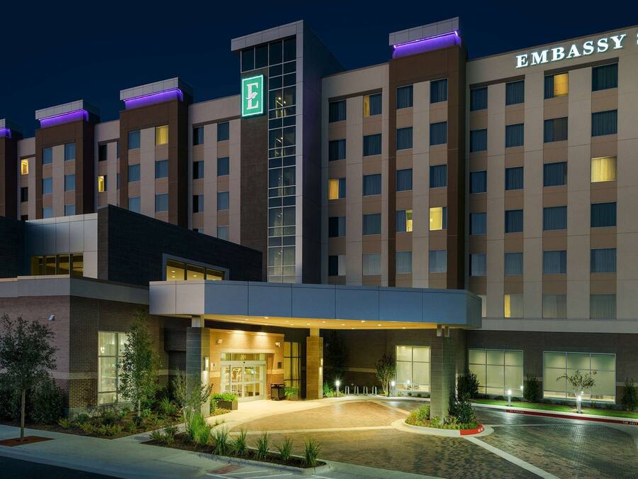 Un hotel con fachada moderna, varios pisos y una entrada destacada con área cubierta.