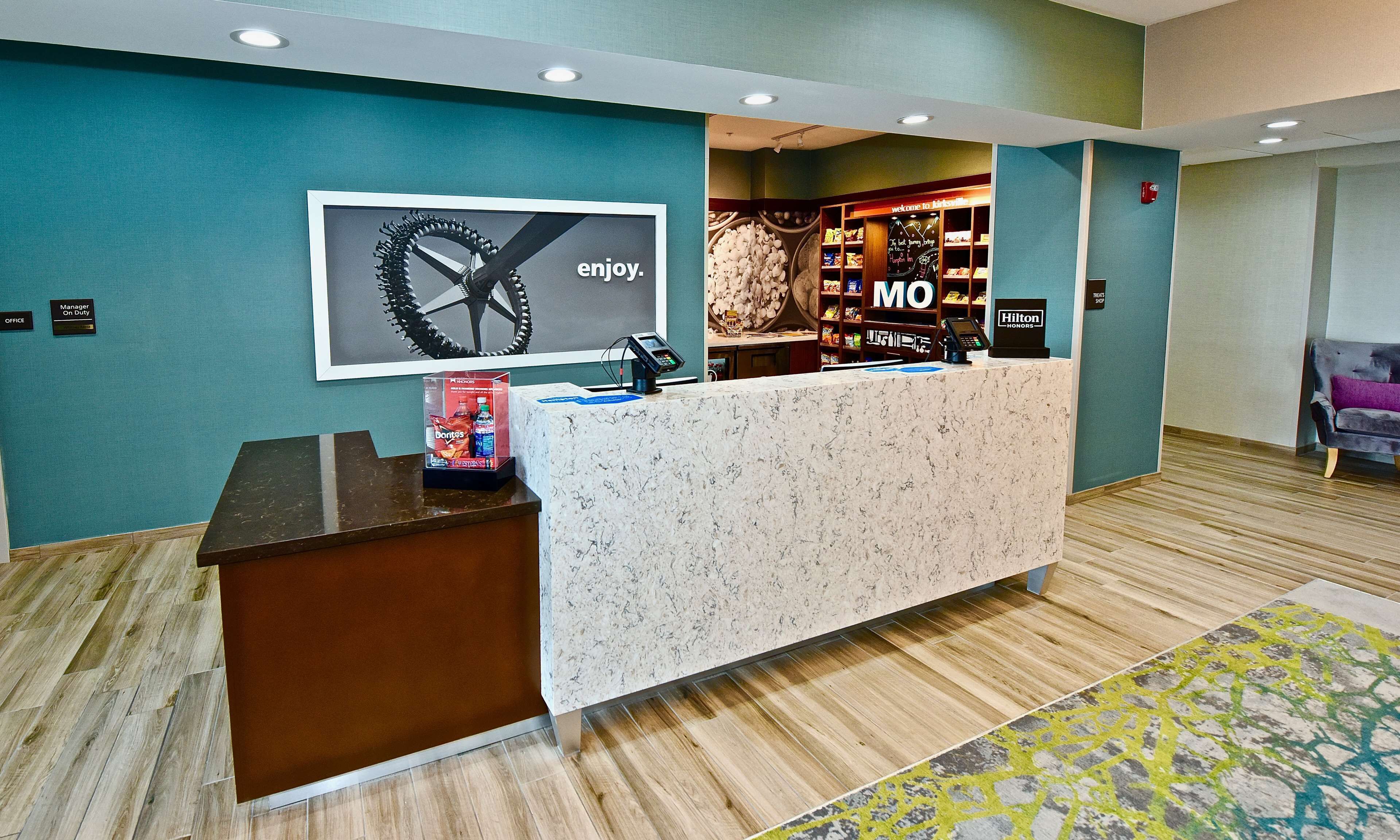 A hotel reception area with a marble counter, a framed artwork, and a minibar.