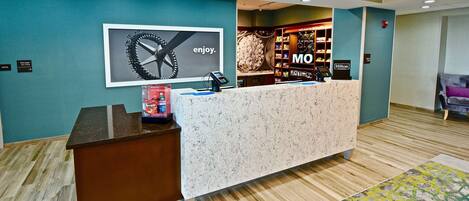 A hotel reception area with a marble counter, a framed artwork, and a minibar.