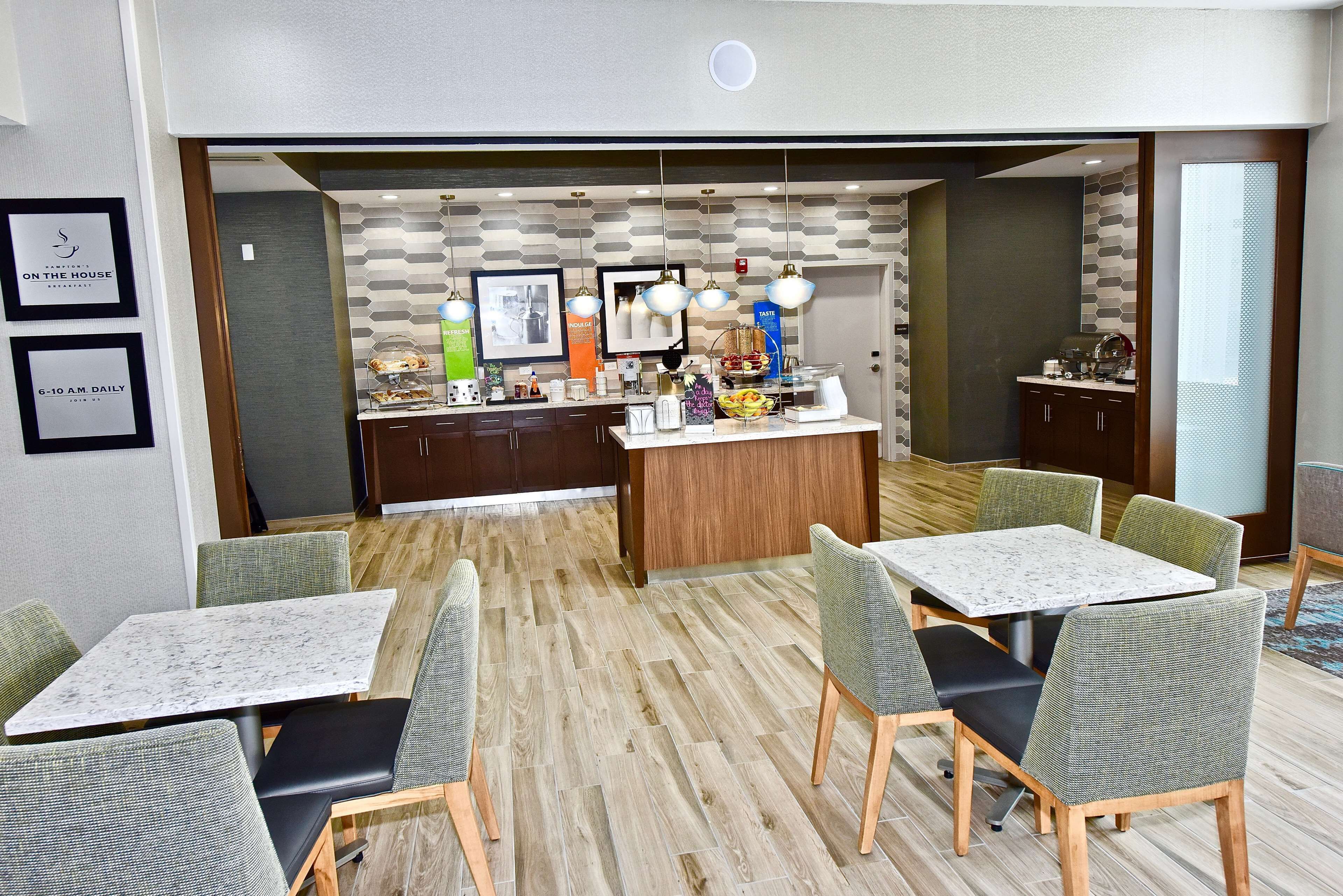 A hotel dining area with a central bar, multiple seating options, and a modern decor.