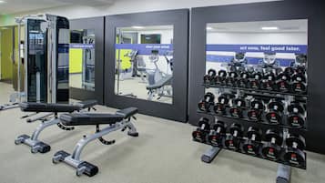 A gym with weightlifting equipment, including dumbbells and a bench press.