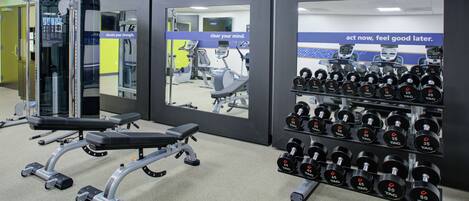 A gym with weightlifting equipment, including dumbbells and a bench press.