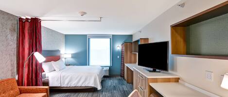 A hotel room with a bed, a desk, a TV, a sofa, and a window.