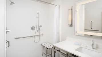 A modern bathroom with a walk-in shower, a vanity with a sink, and a mirror.