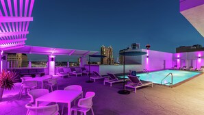 A rooftop pool area with lounge chairs and tables, a pool, and a city skyline view. - Hilton Garden Inn San Antonio Downtown Riverwalk (San Antonio)