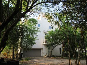 A two-story building with a garage, surrounded by trees.