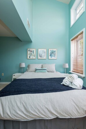 A bedroom with a bed, two bedside tables with lamps, a window with blinds, and three wall art pieces. - Beautiful Federal Hill home! (Baltimore)