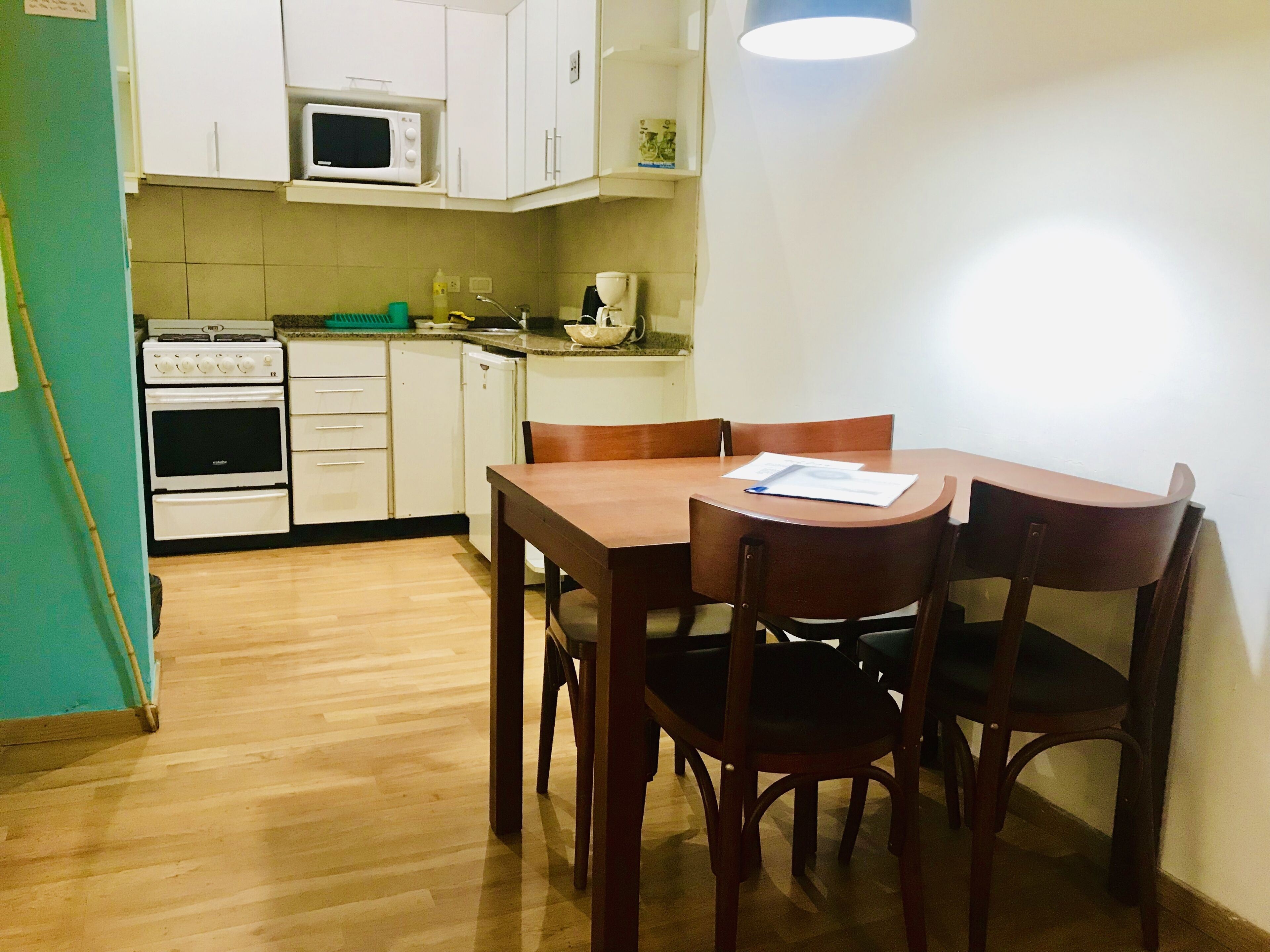 Una cucina funzionale con mobili bianchi, forno a microonde, forno e tavolo con sedie.