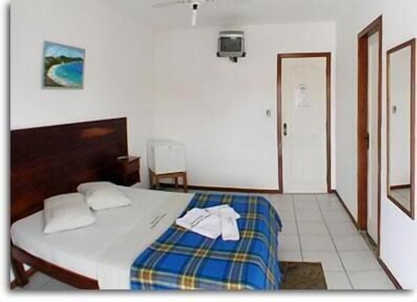 Een slaapkamer met een bed, een stoel, een bureau, een televisie en een deur.