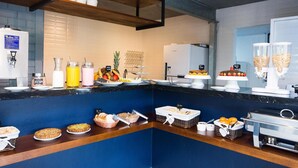 Montaje de bufé con diversas opciones de comida, incluyendo pasteles, frutas y bebidas.
