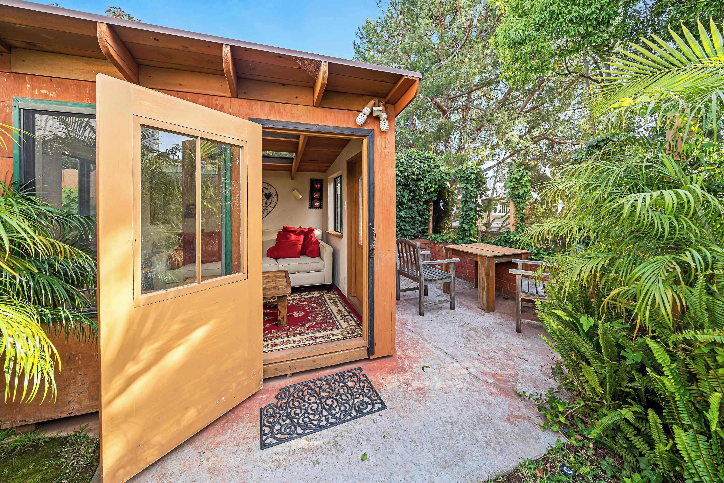 A cozy, open-plan living space with a wooden exterior, a red rug, and a bench.