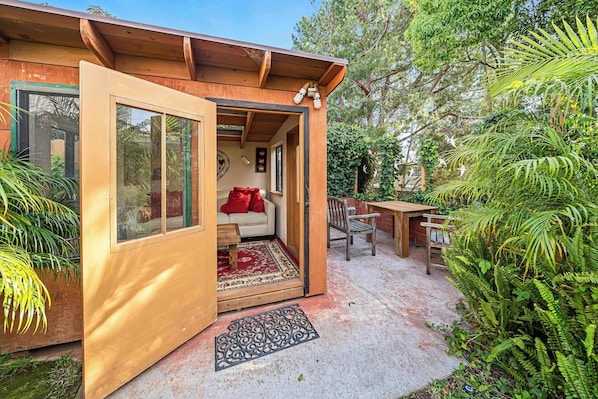 Un espacio habitable acogedor y de planta abierta, con fachada de madera, alfombra roja y un banco.