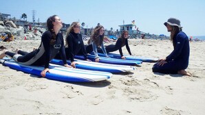 A group of people sitting on the beach with surfboards.