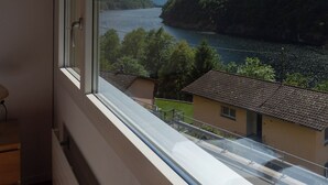 Ein Zimmer mit großem Fenster mit Blick auf einen See und Berge.