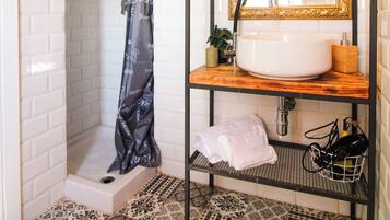 Une salle de bain avec un lavabo blanc, un miroir avec un cadre doré, un rideau de douche et des carreaux de sol à motifs.