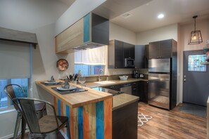 A modern kitchen with a wooden island, stainless steel appliances, and a view to the outside.