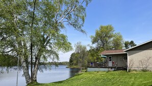 Una propiedad frente al lago con una casa, un porche y un césped.
