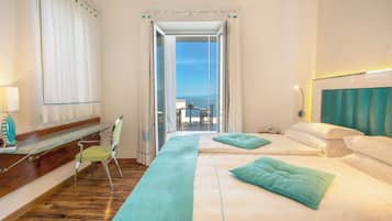 Una camera d'albergo con balcone, una scrivania, una sedia e un letto con testiera.