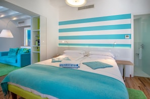 A modern hotel room with a bed, a green sofa, a mirror, and a striped wall design. - Piccolo Grand Hotel (Pizzo)