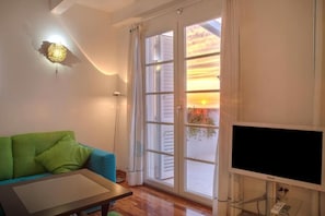 A living room with a sofa, a flat-screen TV, and a sliding glass door leading to a balcony. - Piccolo Grand Hotel (Pizzo)