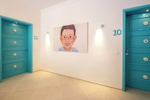 A hallway with teal doors numbered 10 and 11, a tiled floor, and a framed picture on the wall. - Piccolo Grand Hotel (Pizzo)