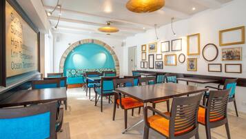 A restaurant with a large wall mural, multiple dining tables, and chairs.