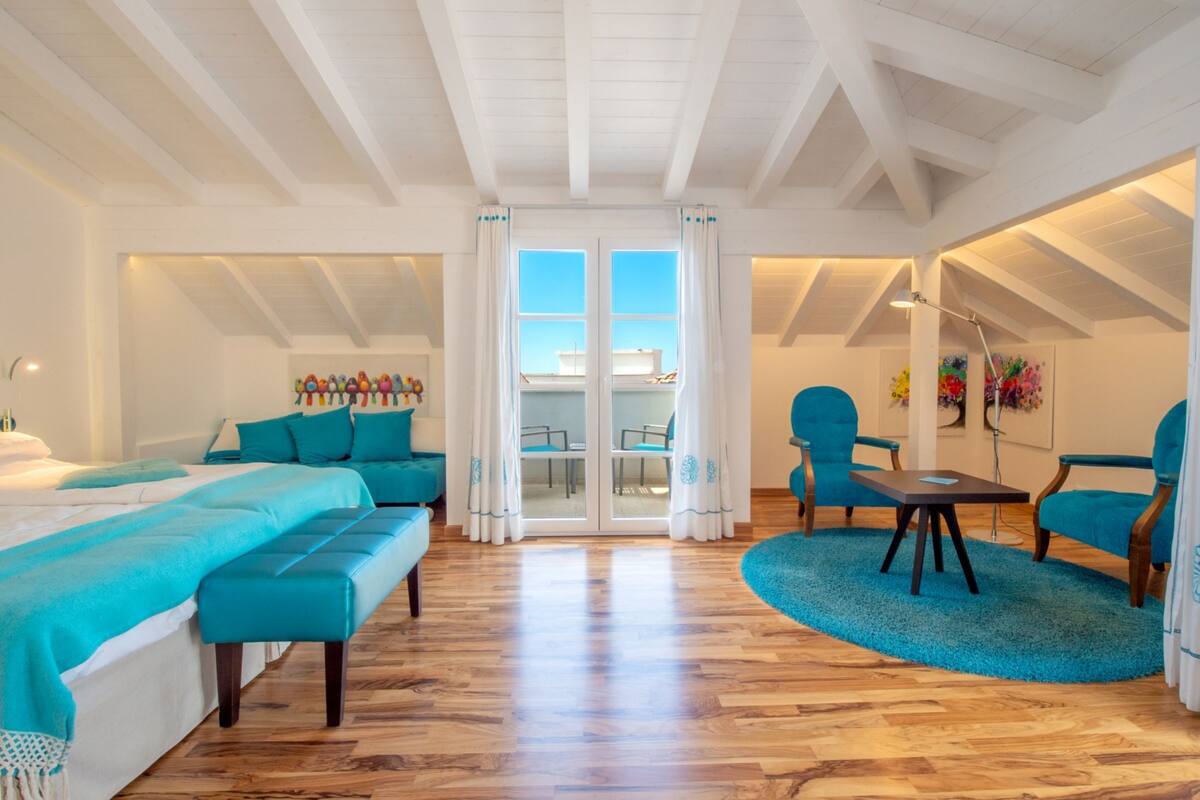 A spacious room with a large bed, a sofa, and a dining area with chairs and a table.
