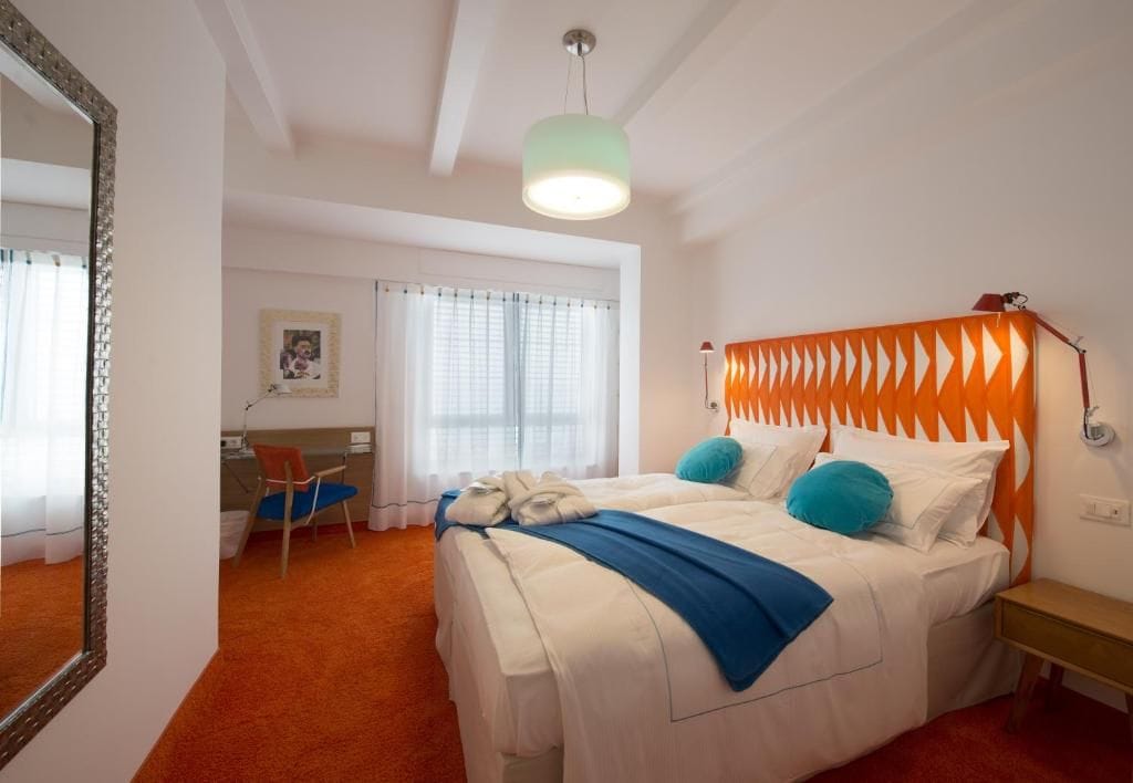 Ein Hotelzimmer mit Bett, Schreibtisch, Stuhl und einem großen Spiegel.