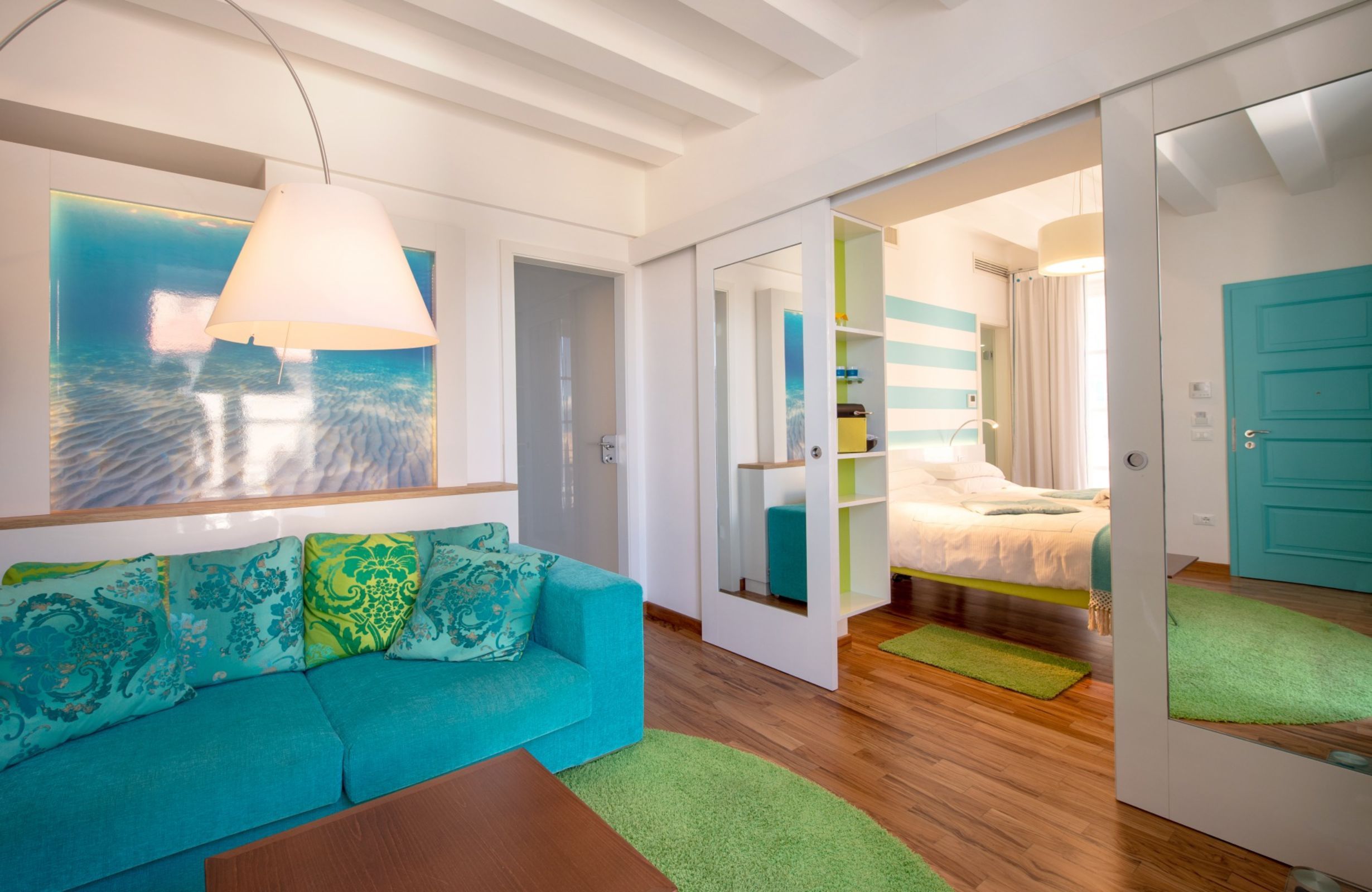 A modern room with a sofa, a bed, a wardrobe, and a view of the sea.